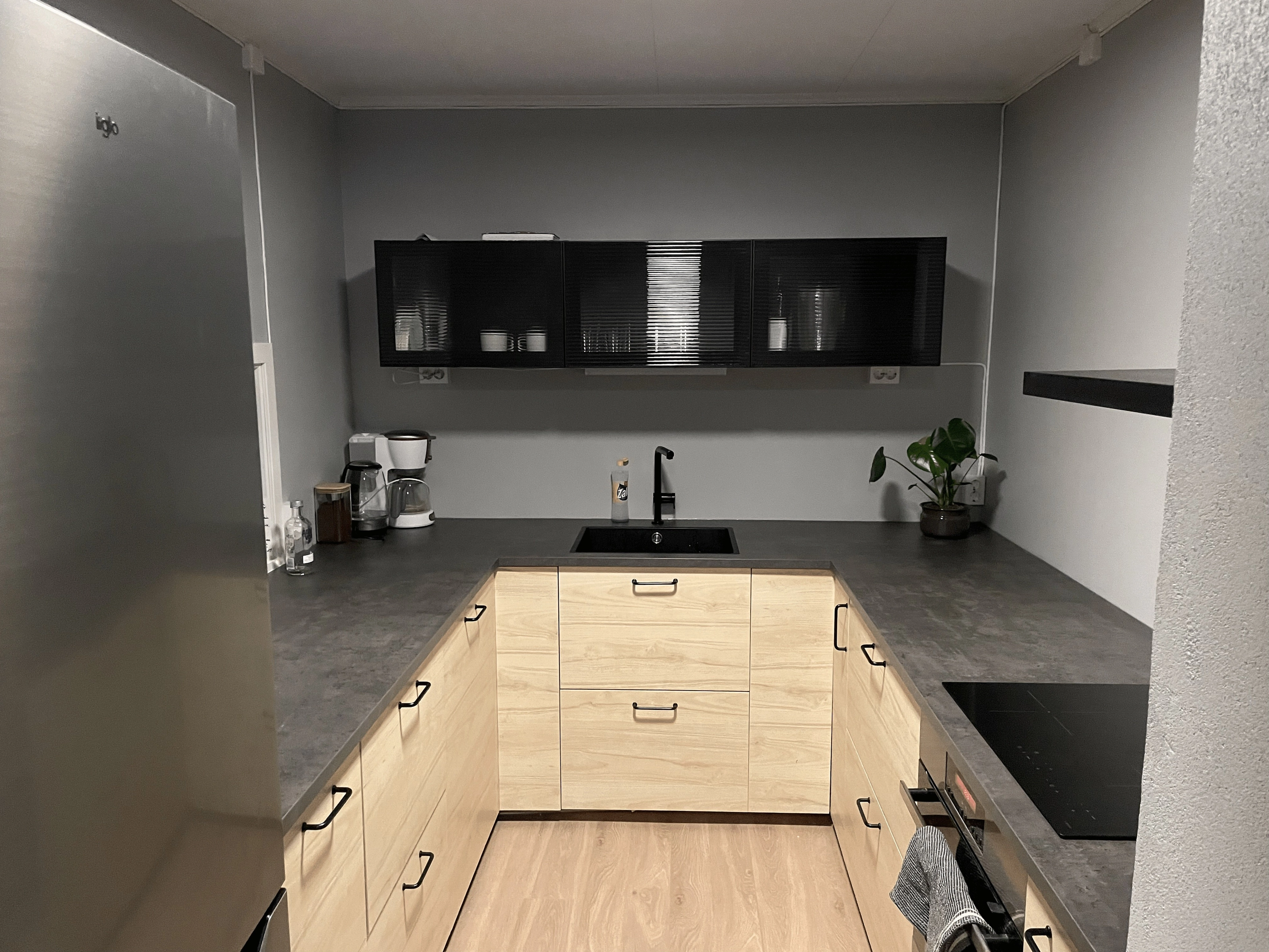 New kitchen with light wood and black upper cabinets after renovation.